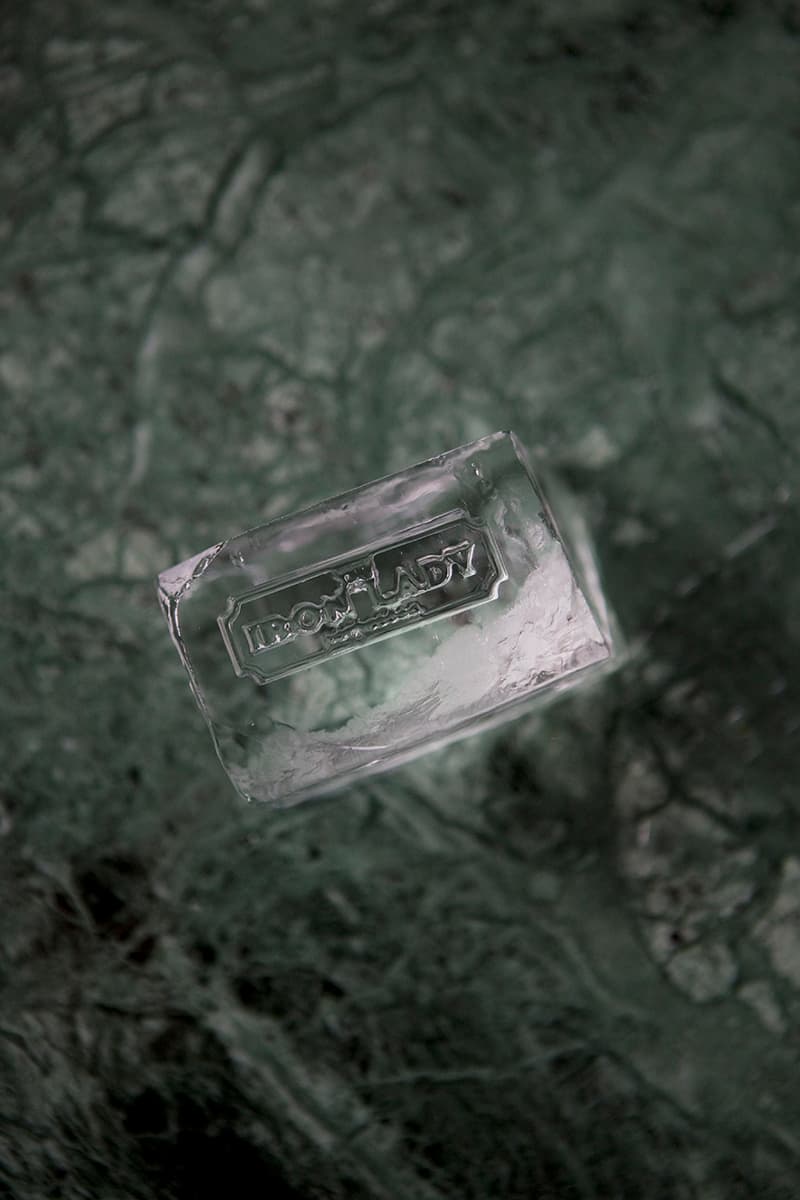 An Iron Lady branded ice cube on green marble at the bar