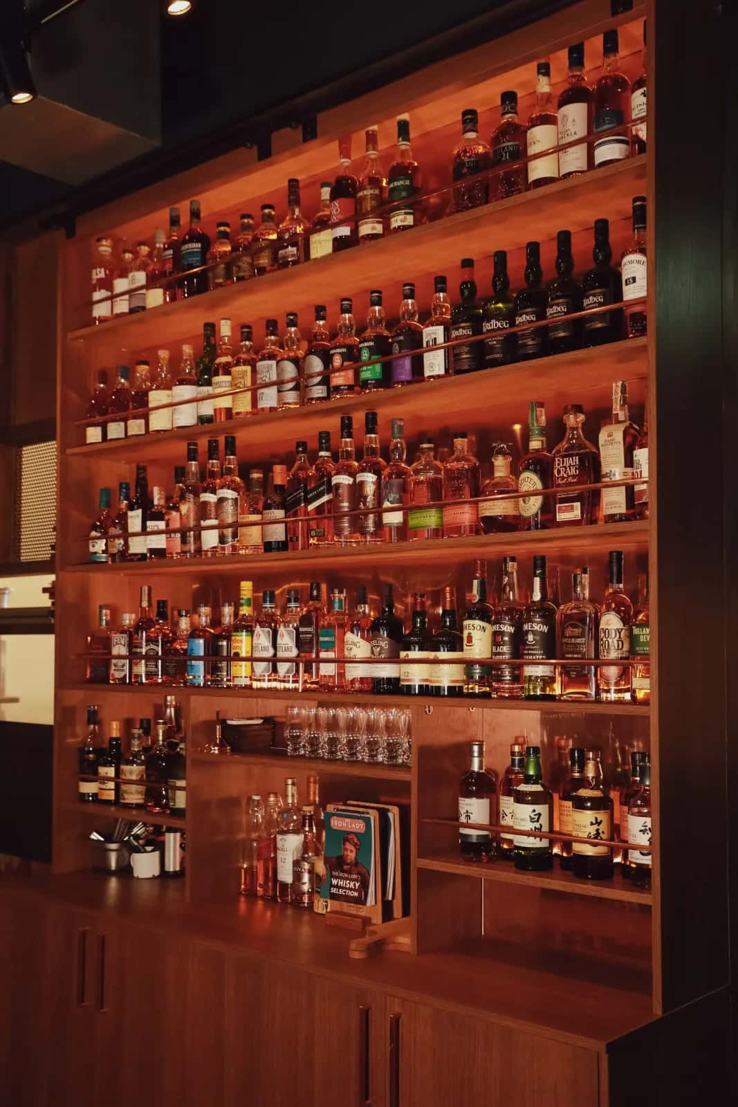 The warmly-lit back-bar at The Iron Lady, lined with whisky and spirits